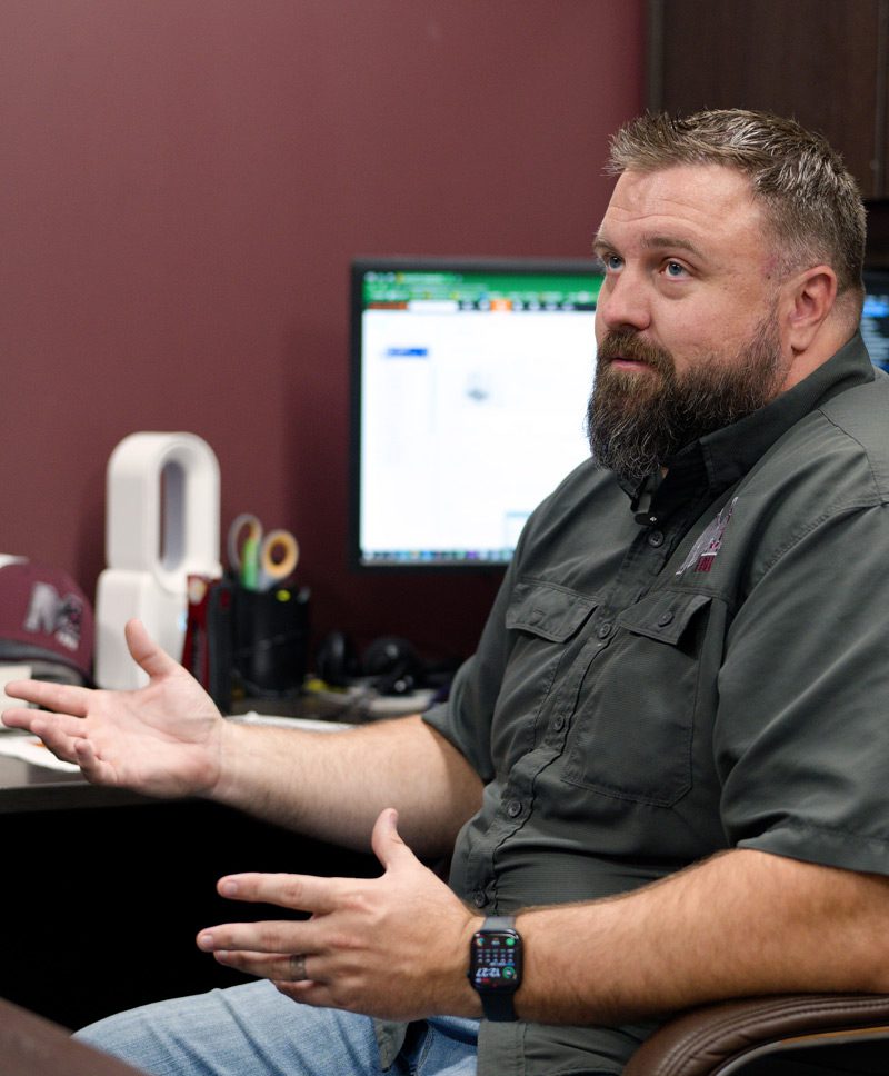 Tyler McClure sits at his desk explaining the design capabilities of his company