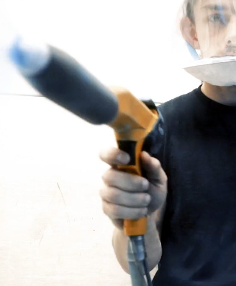 M3 employee operates a powder coating spray wand